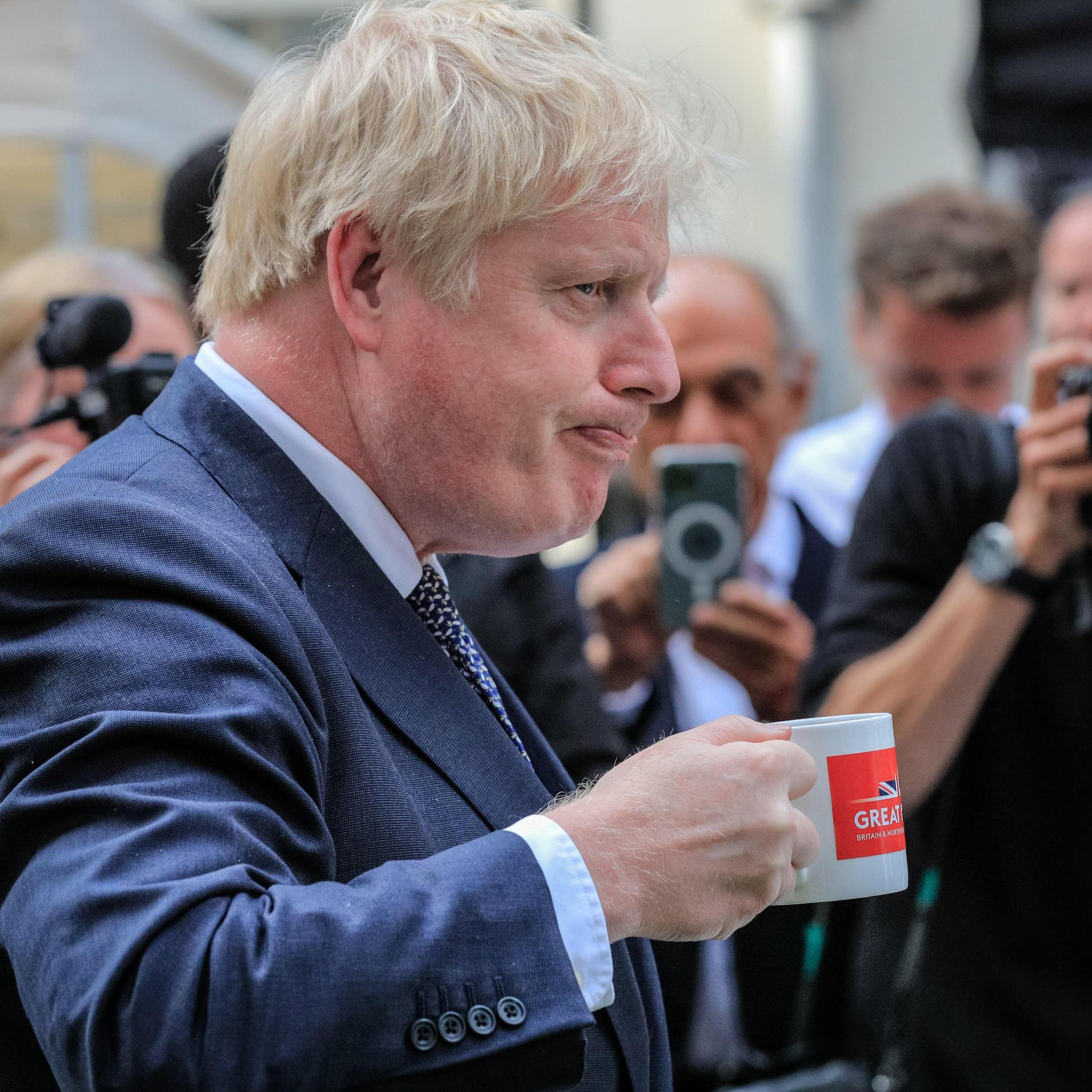 Boris Johnson drinking from a mug.