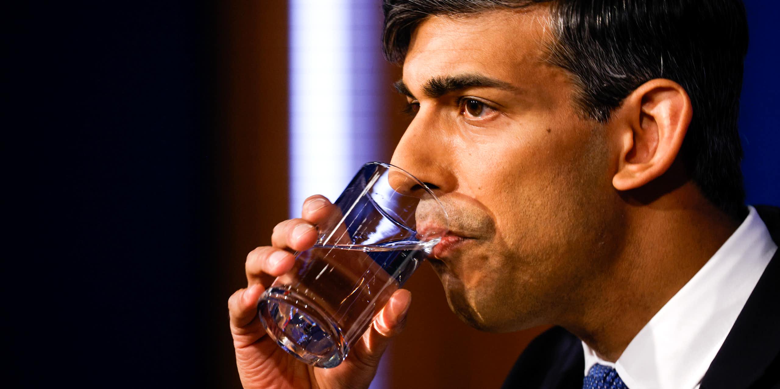 Rishi Sunak drinking a glass of water, looking tense.