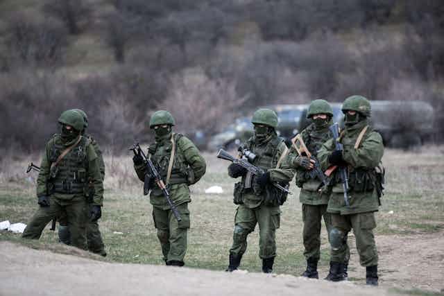 Soldiers wearing green and carrying weapons.