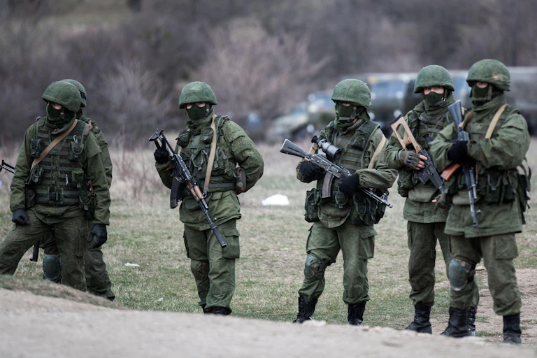 Soldiers wearing green and carrying weapons.