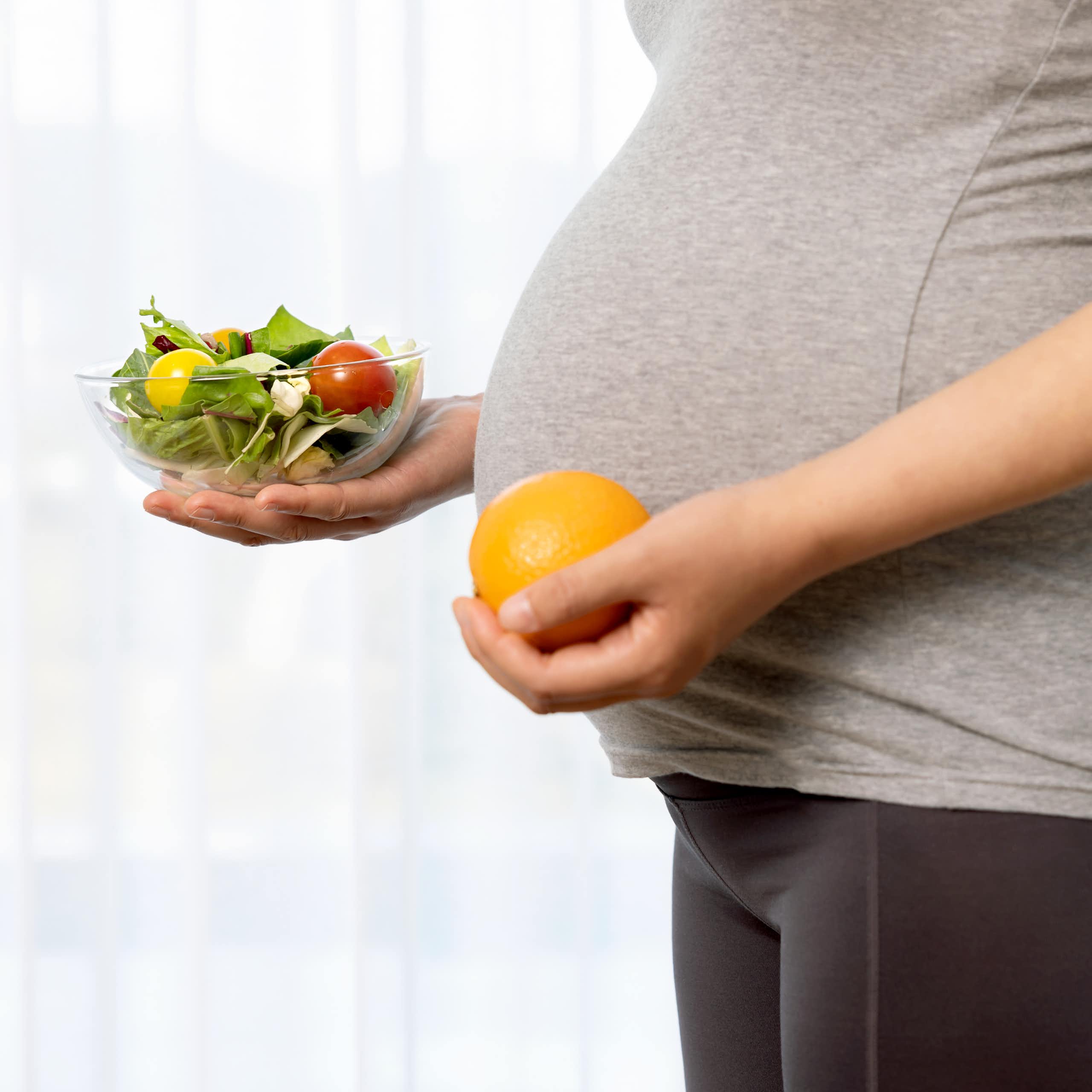 Pregnant woman holding a bowl of fruit