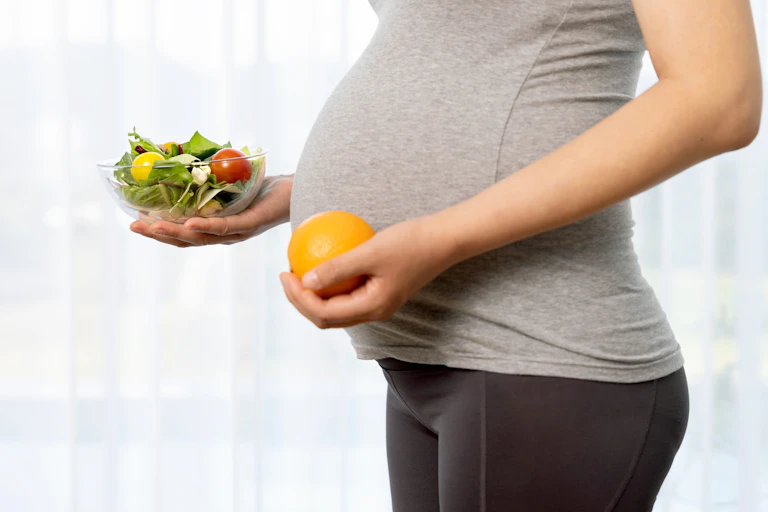 Pregnant woman holding a bowl of fruit