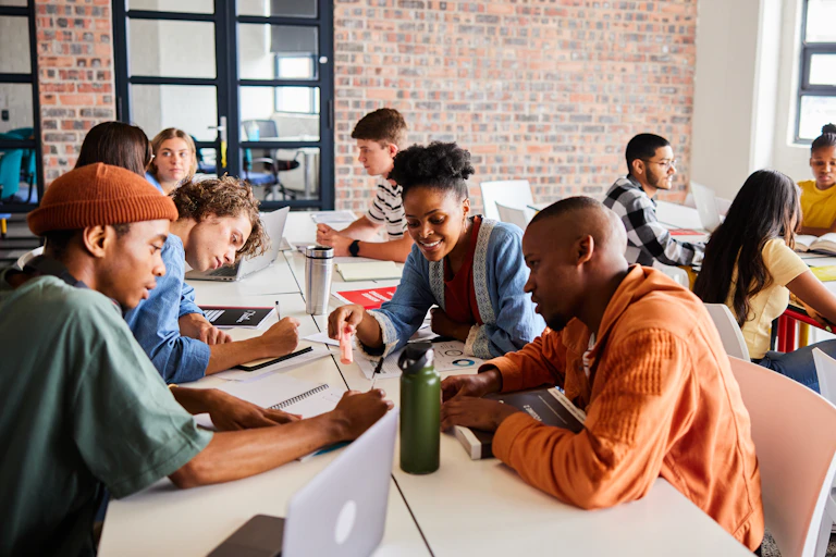 A diverse group of university students working together while sitting around a table between classes