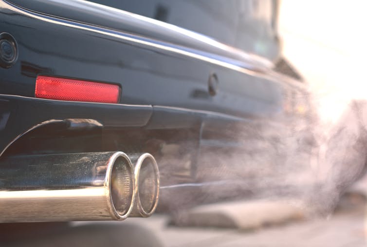 Close up of smoky dual exhaust pipes from a starting diesel car