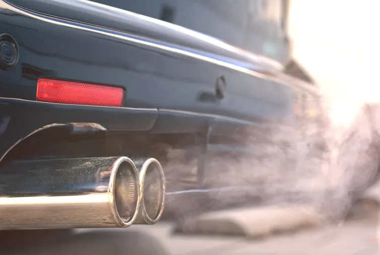 Close up of smoky dual exhaust pipes from a starting diesel car