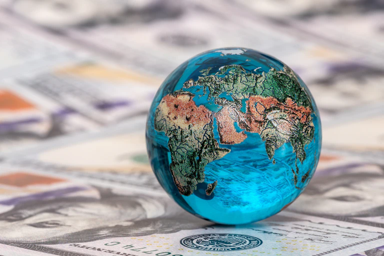 un globe terrestre reposant sur un tapis de billets de banques