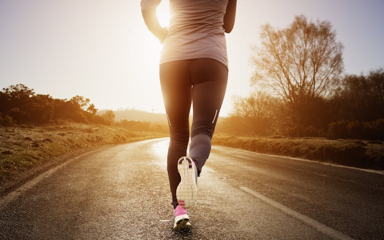 woman in exercise gear running away from camera, showing back down to sneakers