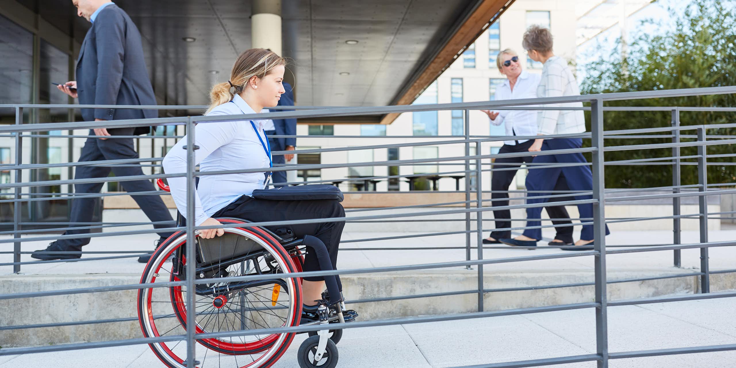 Une femme en fauteuil roulant circule dans une rampe pour personne à mobilité réduite