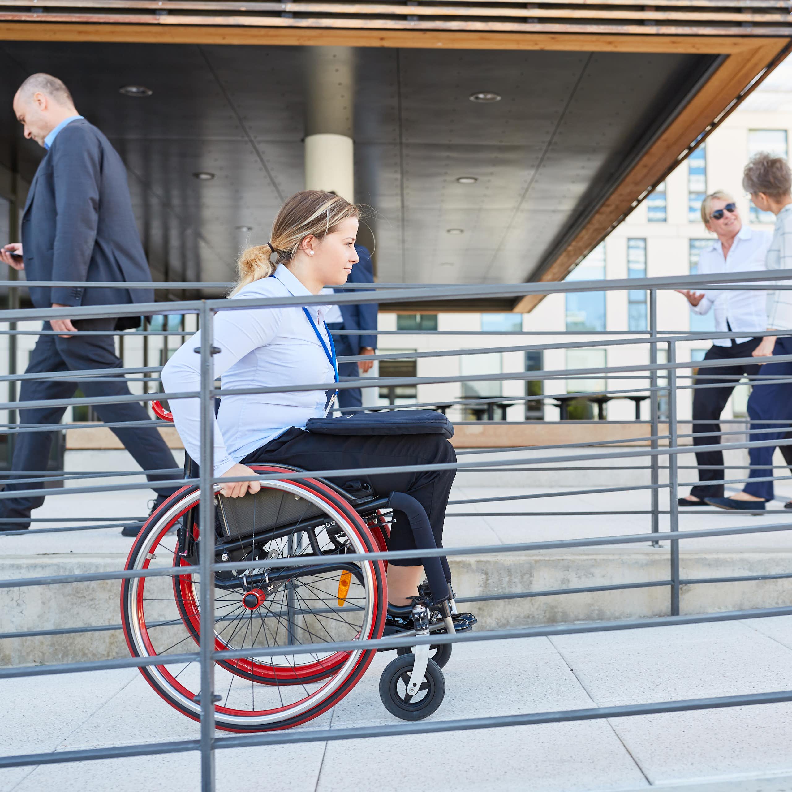 Une femme en fauteuil roulant circule dans une rampe pour personne à mobilité réduite