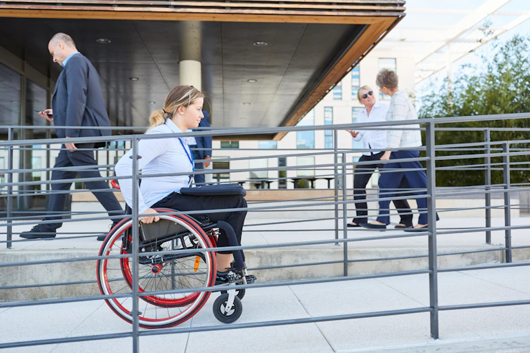 Une femme en fauteuil roulant circule dans une rampe pour personne à mobilité réduite