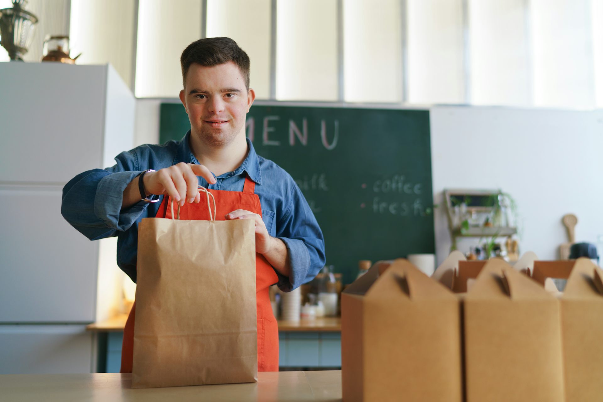 Un jeune homme ayant une trisomie remplit des sacs de victuailles, dans un restaurant