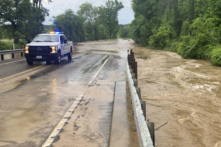 A truck is parked along a highway covered by floodwater.
