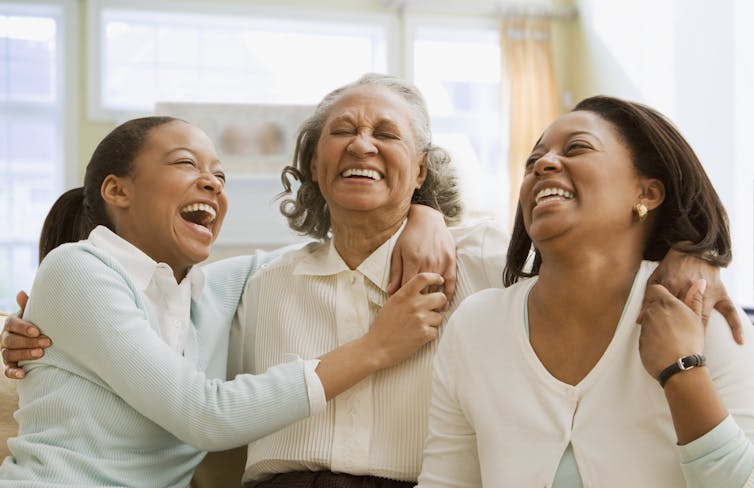 Girls, older woman and middle-aged women laugh with their arms around each other