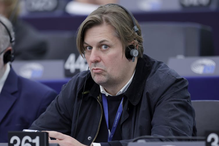 Maximilian Krah sitting in the European parliament wearing translation headphones.