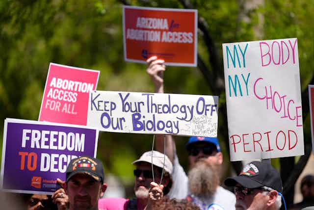 Abortion rights supporters hold up signs of protest against the Arizona abortion ban.