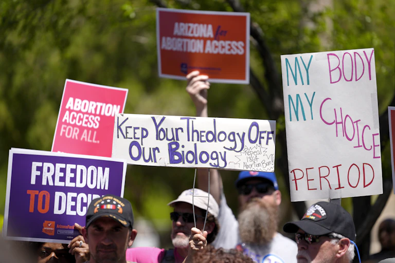 Abortion rights supporters hold up signs of protest against the Arizona abortion ban.
