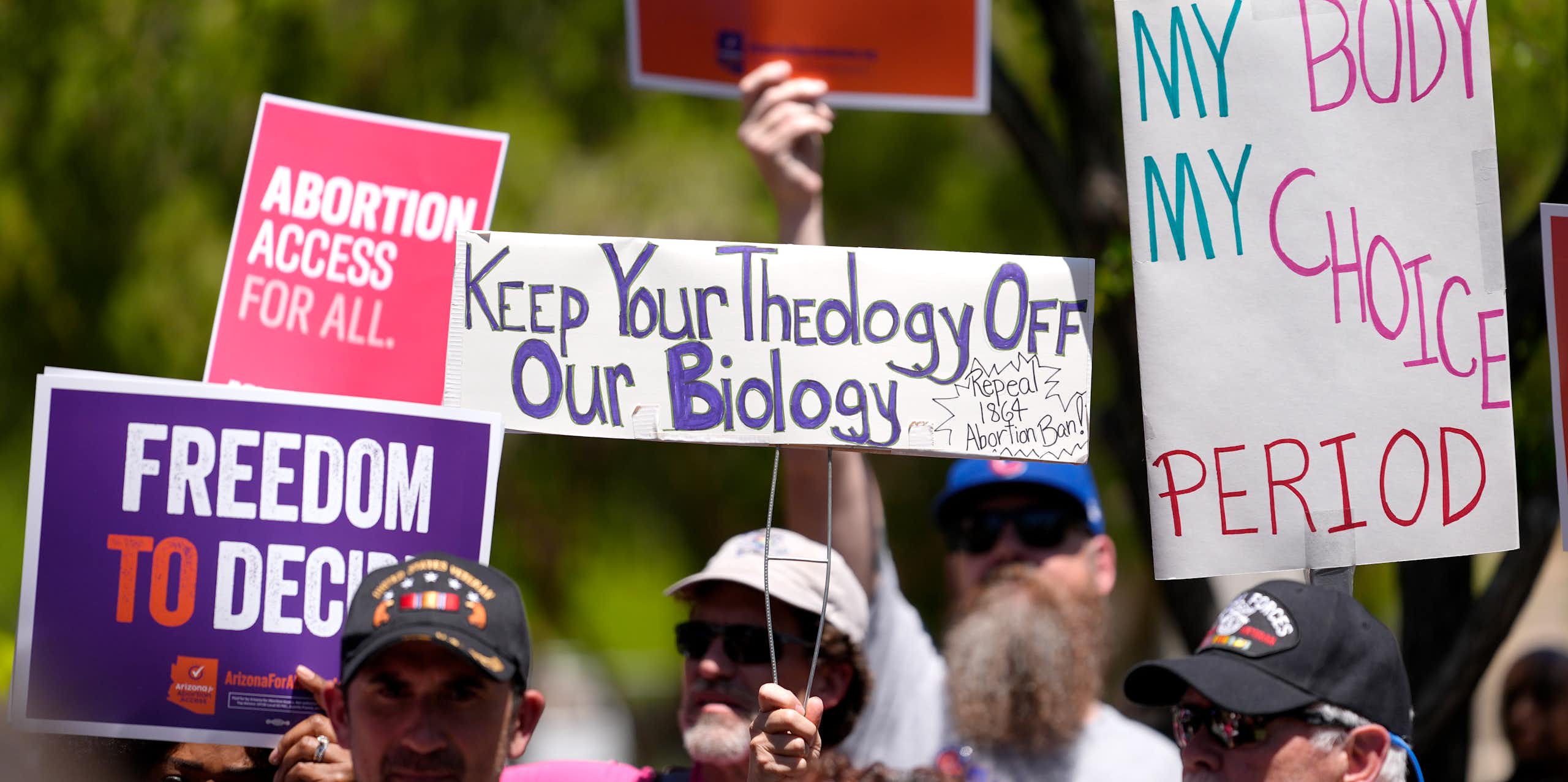 Abortion rights supporters hold up signs of protest against the Arizona abortion ban.