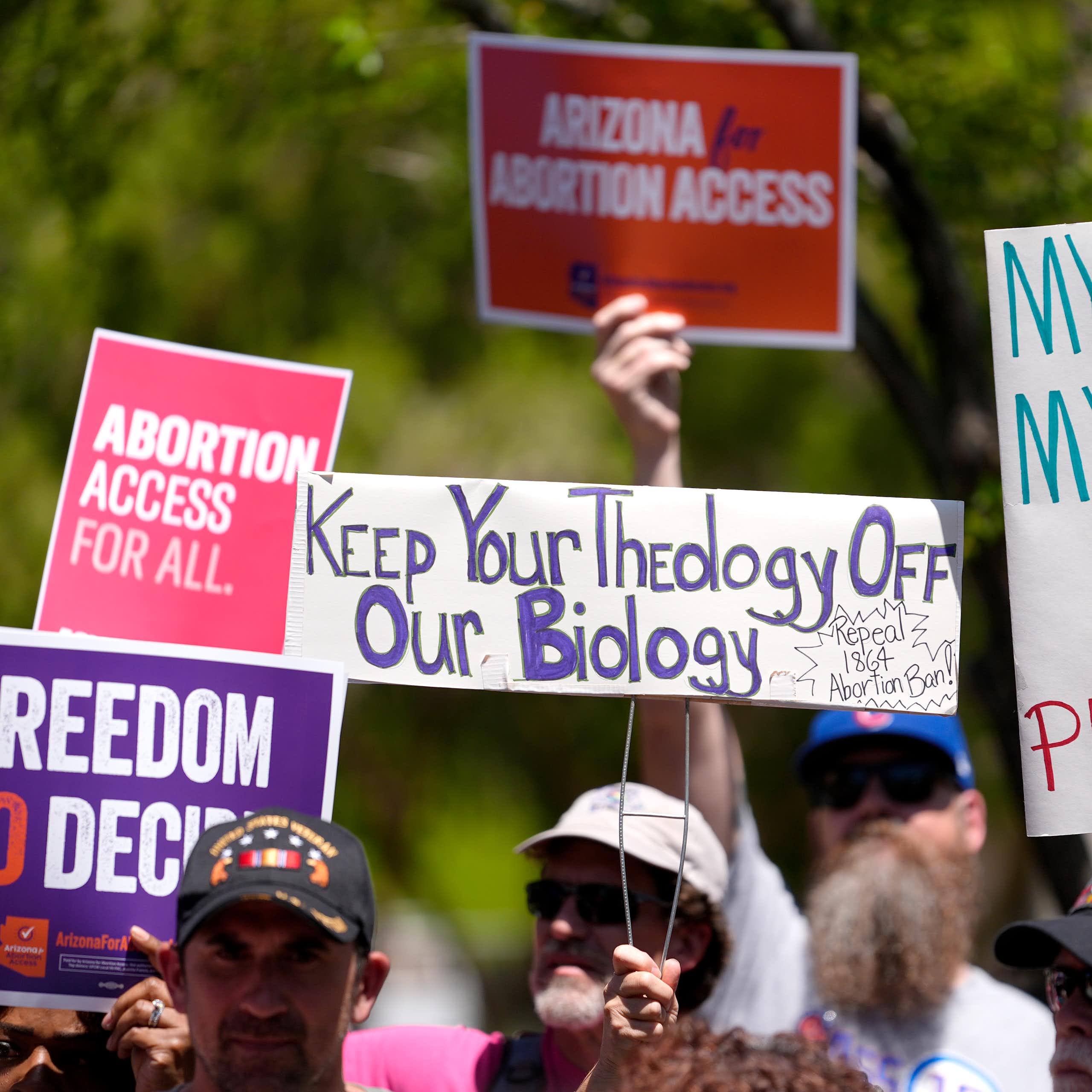 Abortion rights supporters hold up signs of protest against the Arizona abortion ban.