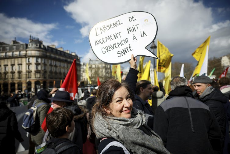 A woman carrying a sign at a protest in French