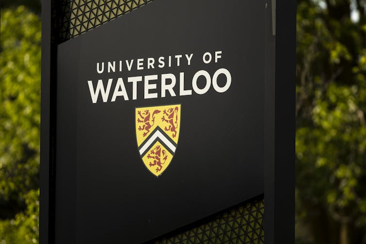 A black sign reading: University of Waterloo with the university's logo