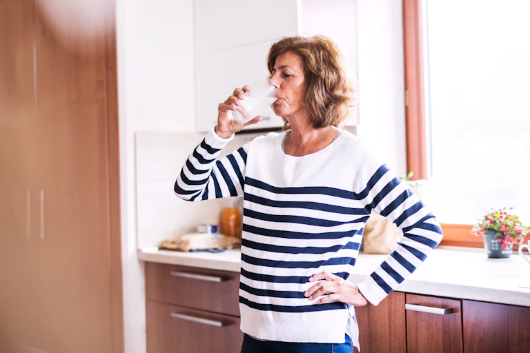 Woman drinks water after swallowing pill