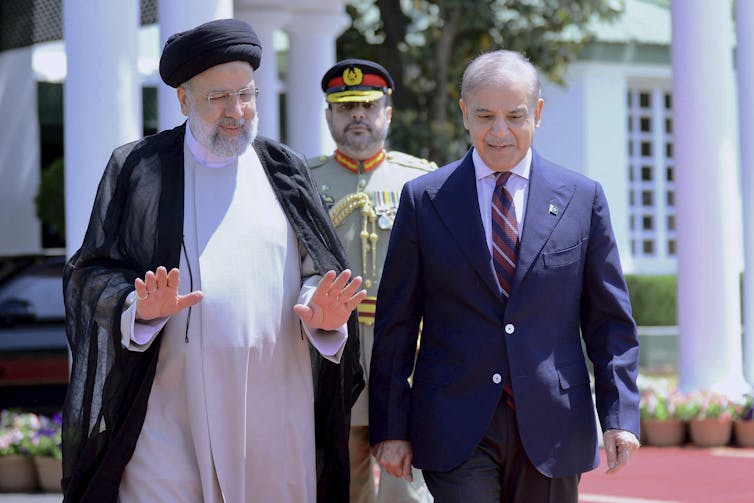 Iranian President Ebrahim Raisi, left, walks with Pakistani Prime Minister Shehbaz Sharif.