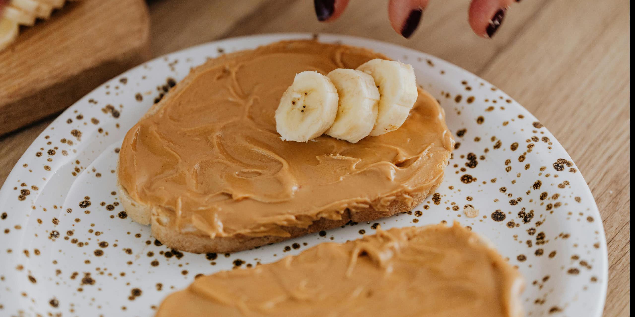 Person puts banana on toast with peanut butter