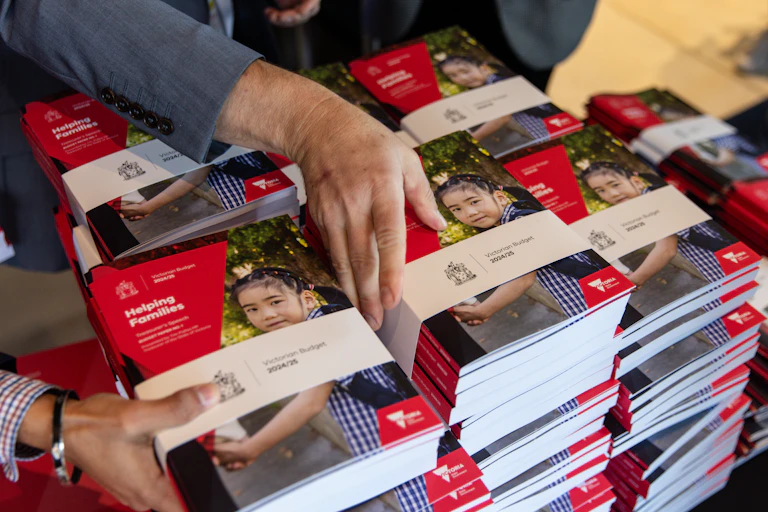 Unidentified hands grab books from large piles stacked on a table
