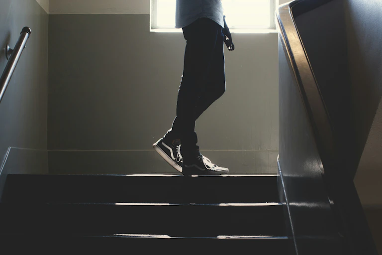 A man stands at the top of a dimly lit staircase.