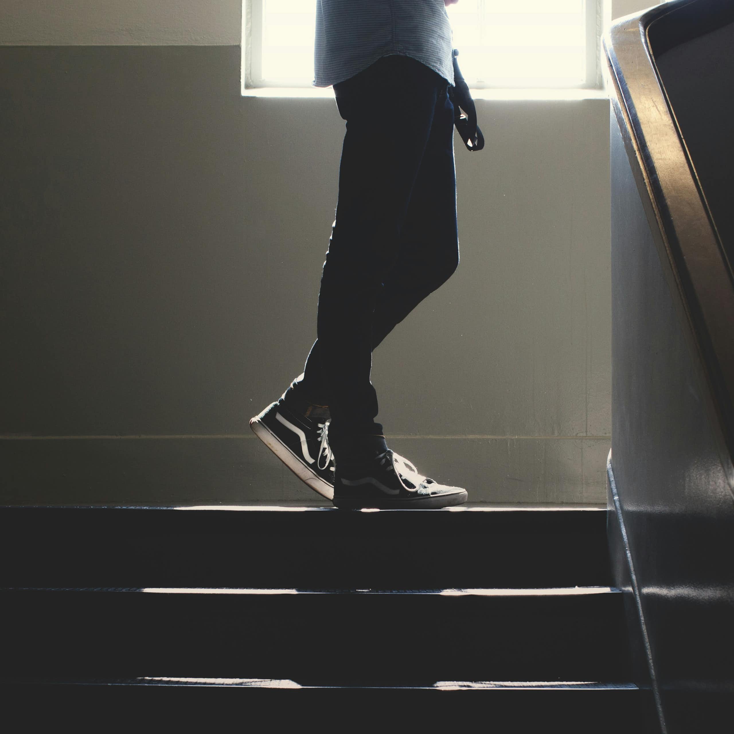 A man stands at the top of a dimly lit staircase. 