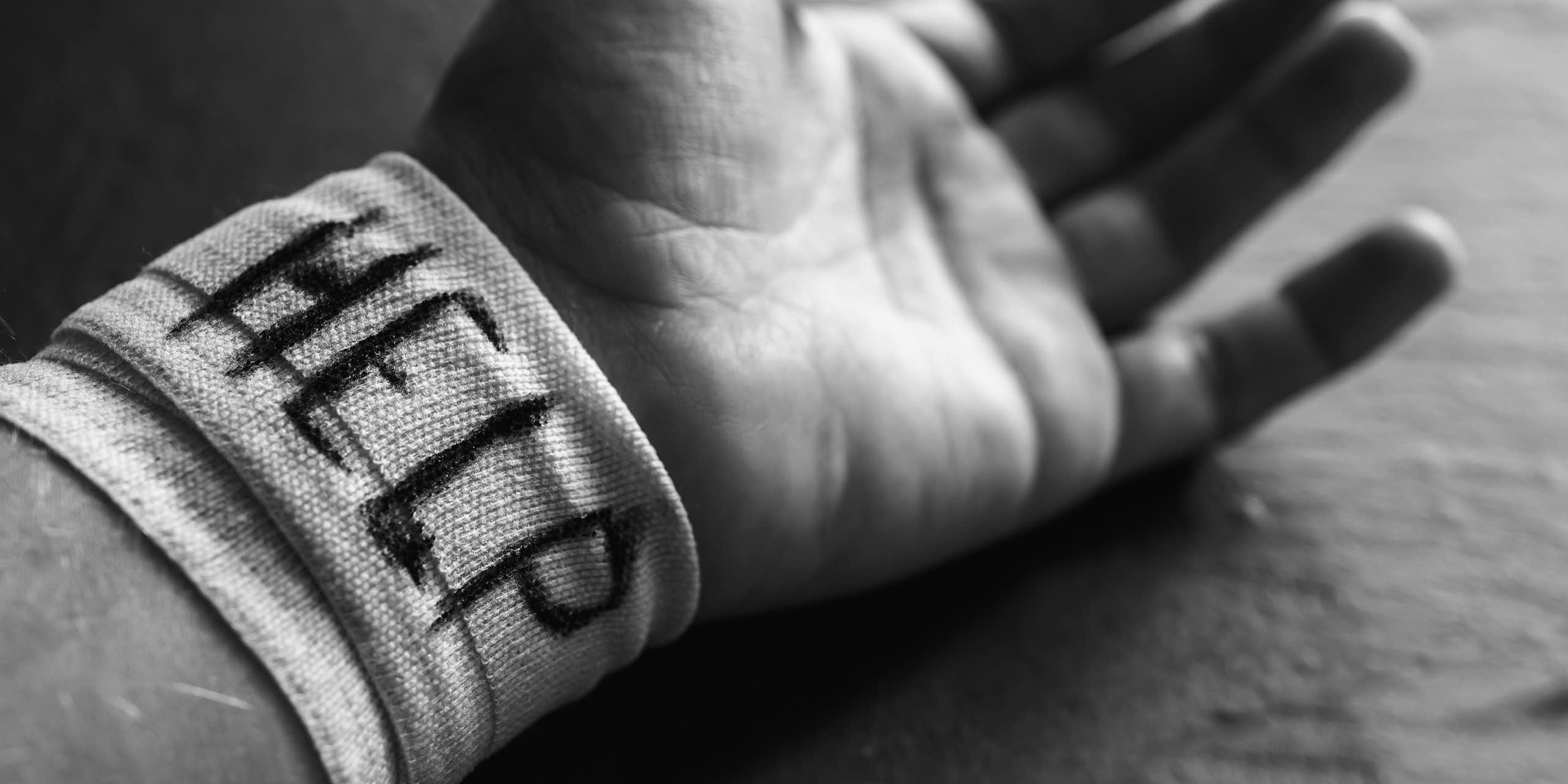 A hand with 'HELP' written on its bandaged wrist