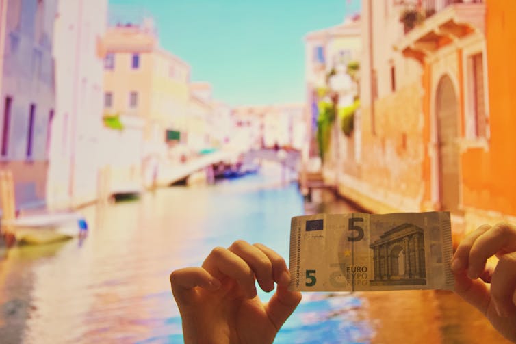 A €5 note with Venice scene background.