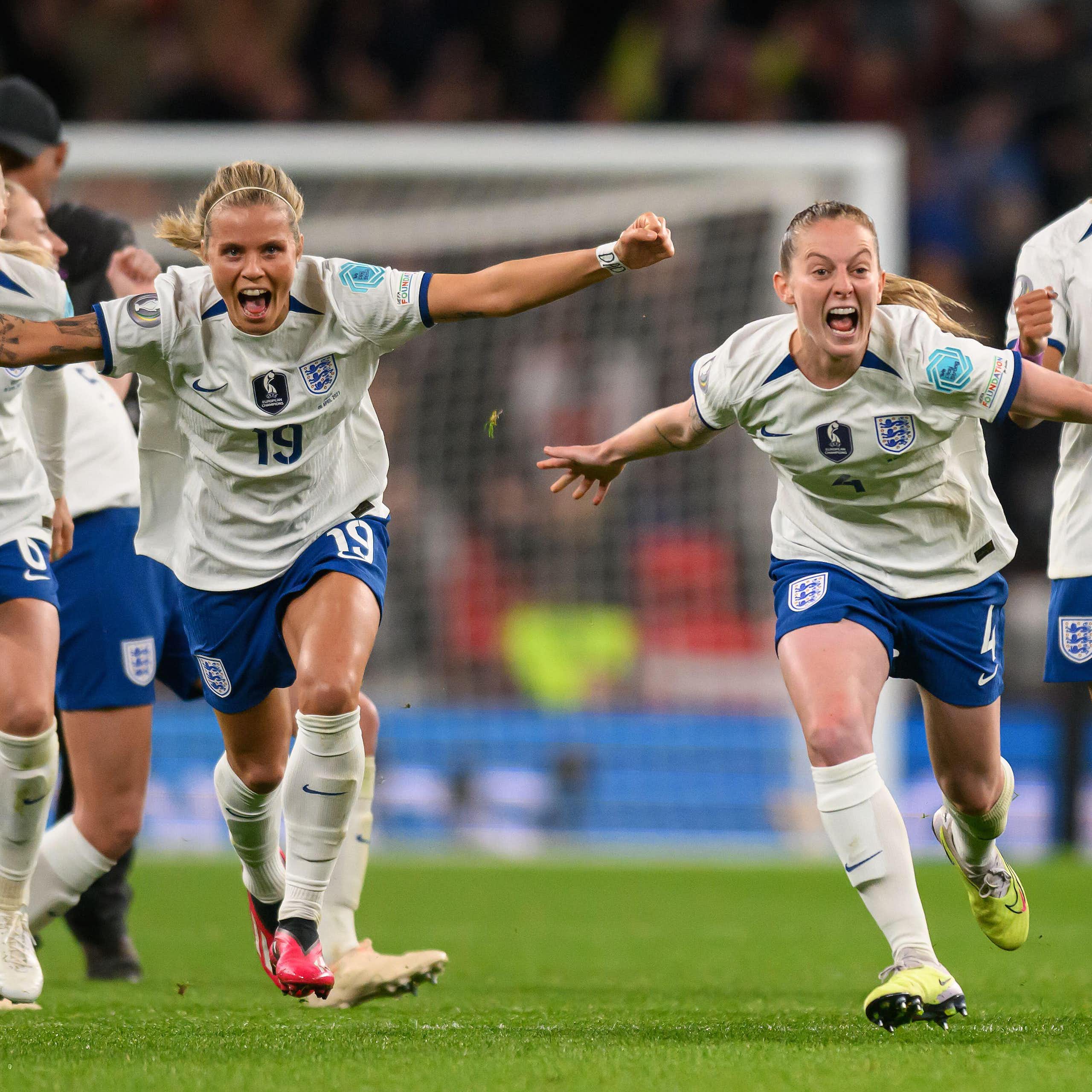 A group of England women footballers celebrate with arms spread. 