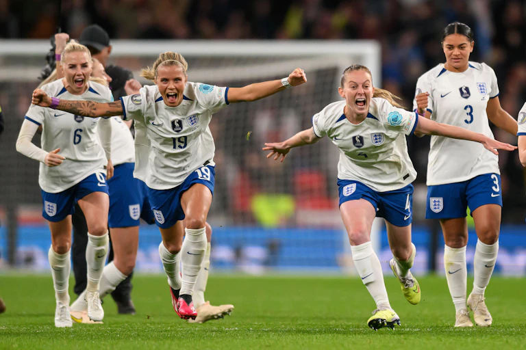 A group of England women footballers celebrate with arms spread.