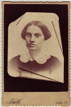A black and white yellowed photo of a woman wearing a lace collar dress.
