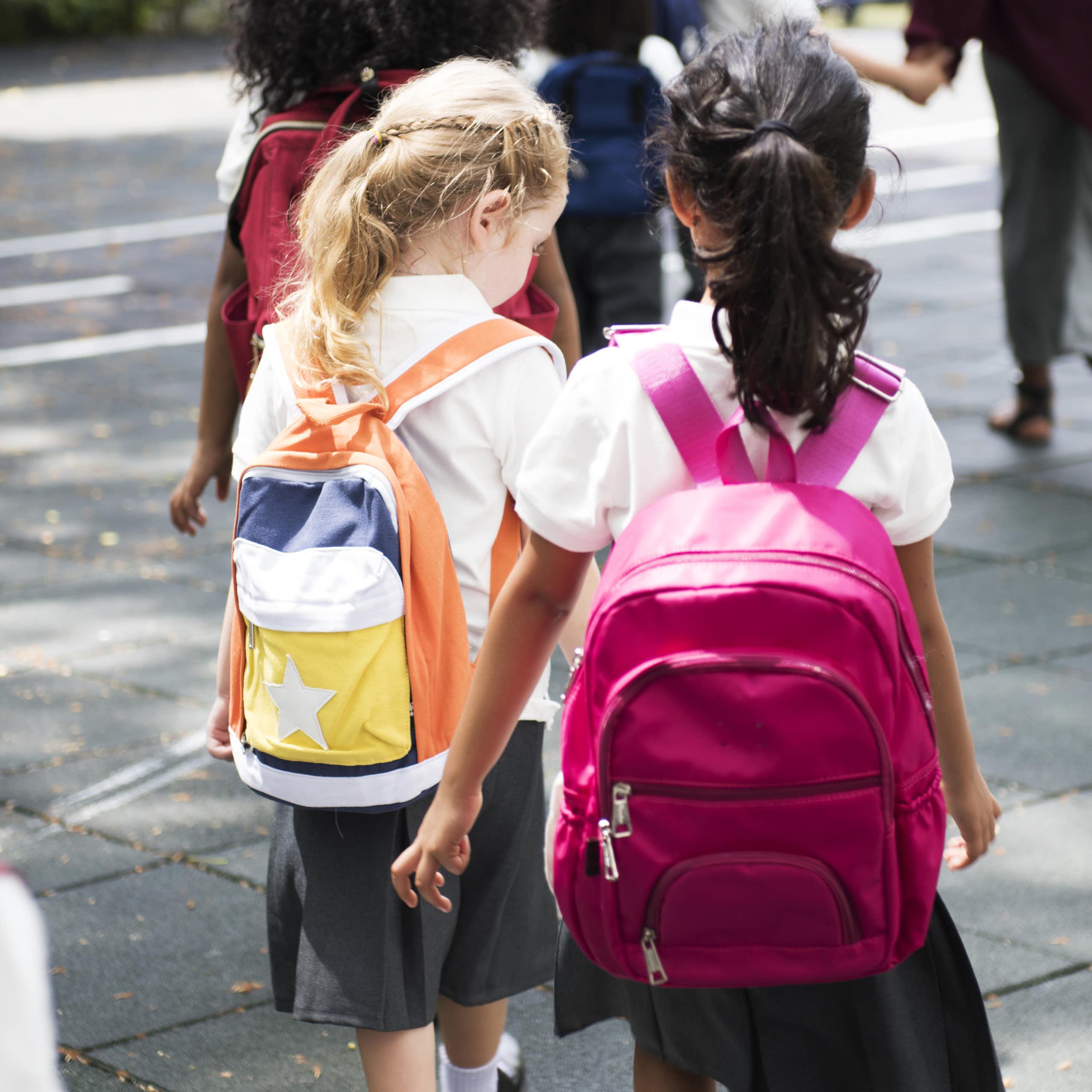 Children in uniforms and rucksacks walking to school