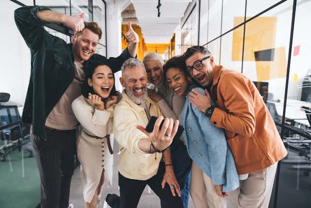 A group of smiling coworkers taking a selfie together in the office