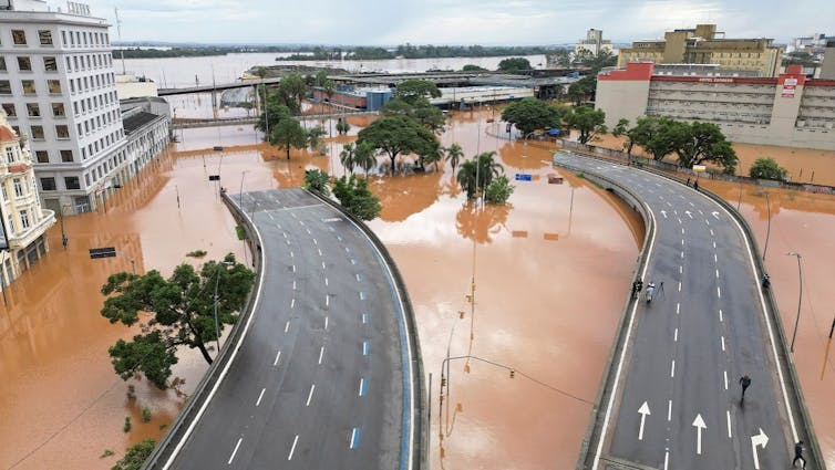 Foto mostra ruas debaixo d'água. Só a parte mais alta de um viaduto está acima das águas. Ao lado, prédios e casas.