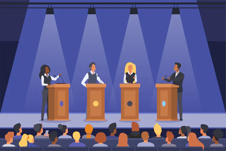 Four people on stage behind lecterns, in a meeting hall.