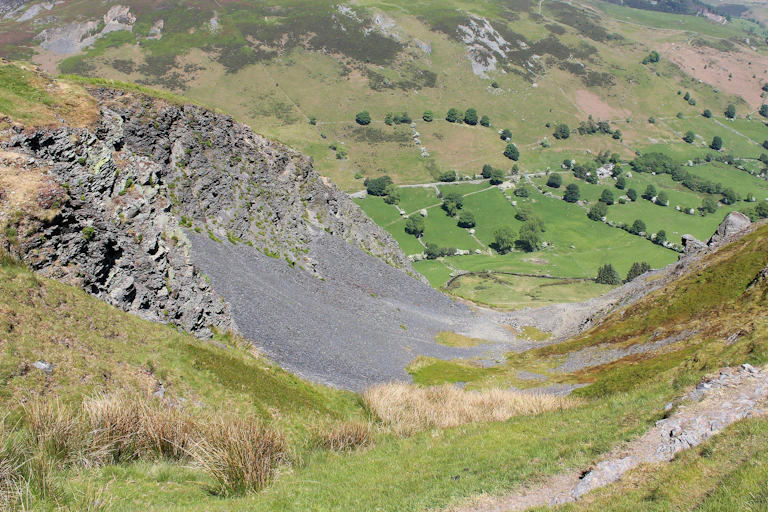Wide green hilly landscape with black scree on hill in foreground