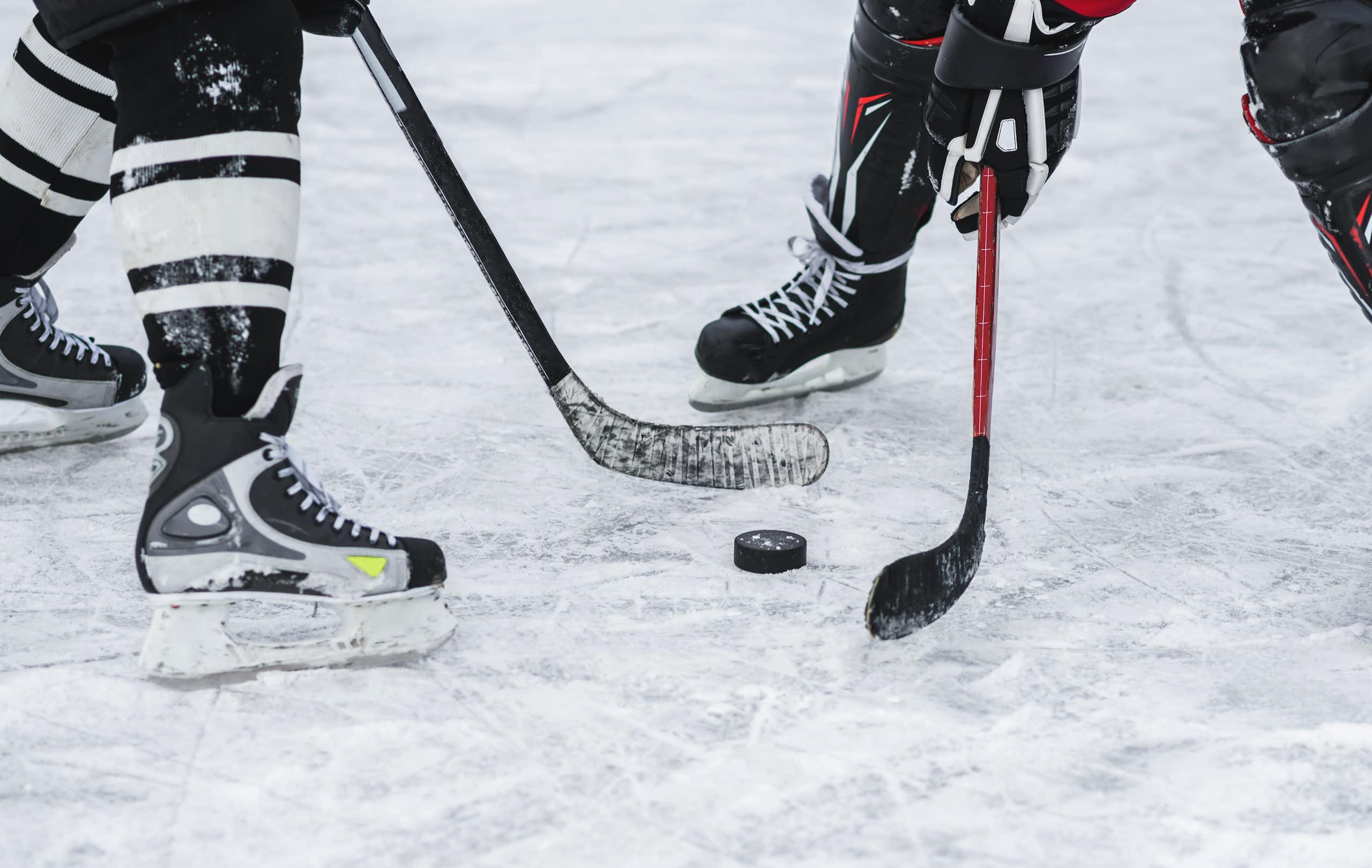 Close up of the skates of two hockey players battling for the puck on a skating rink