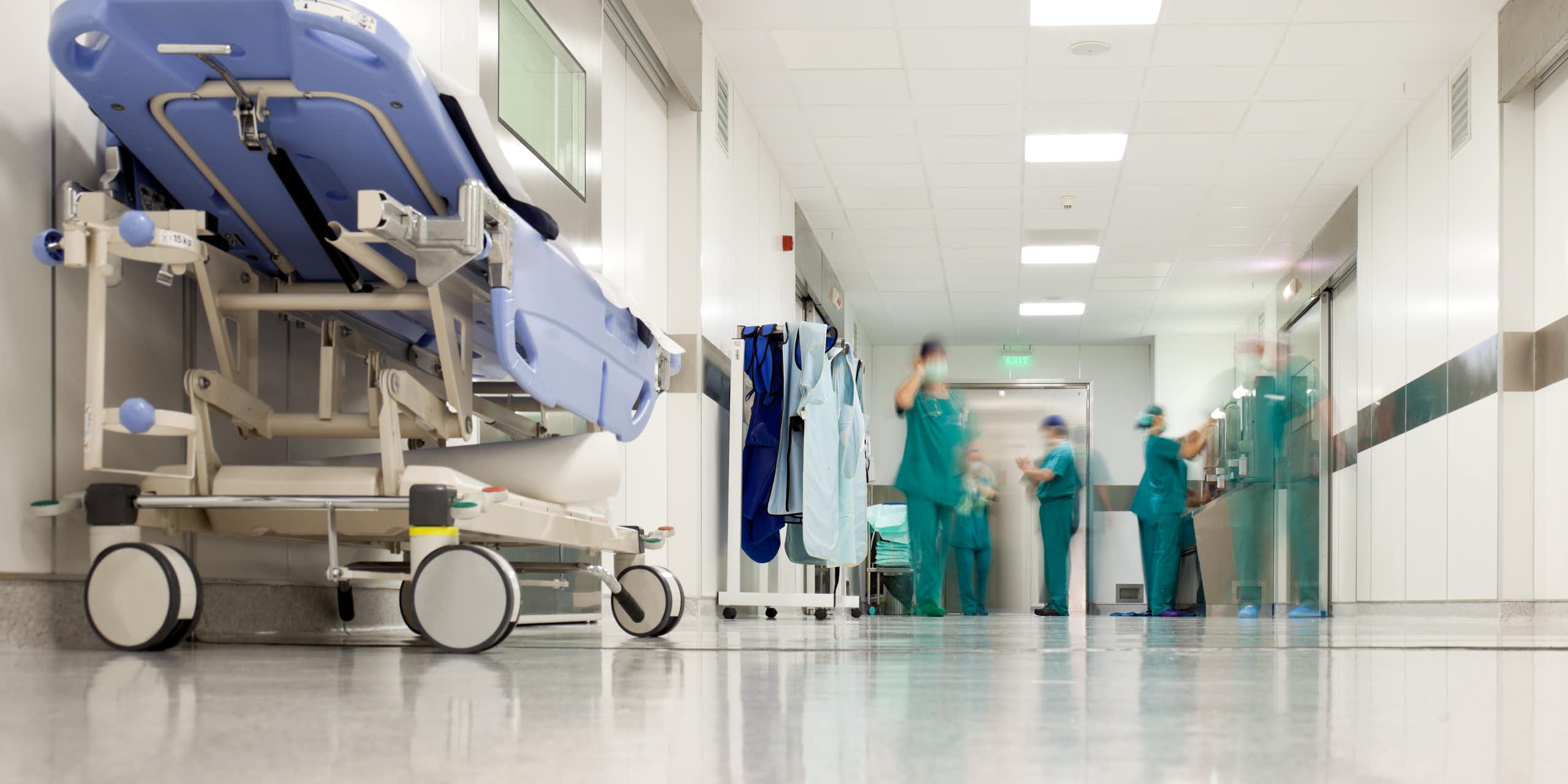 Health-care workers in green scrubs in a hospital corridor