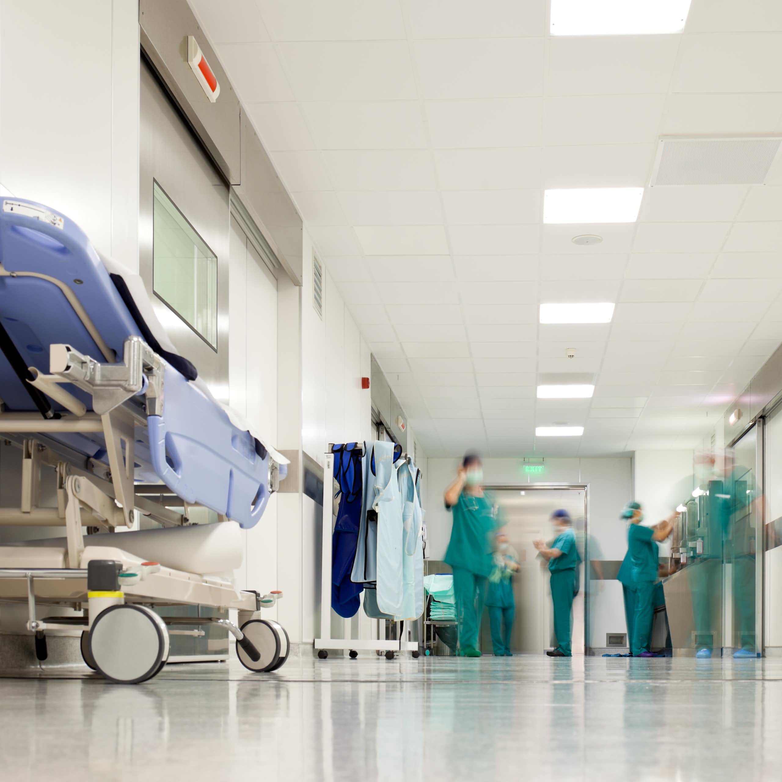 Health-care workers in green scrubs in a hospital corridor