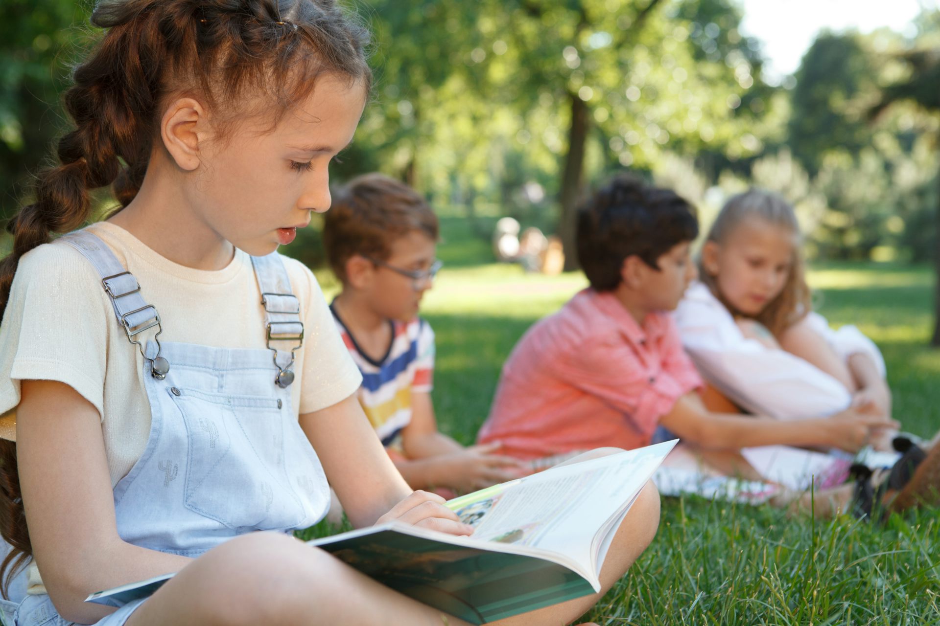Des enfants lisent assis dans l’herbe