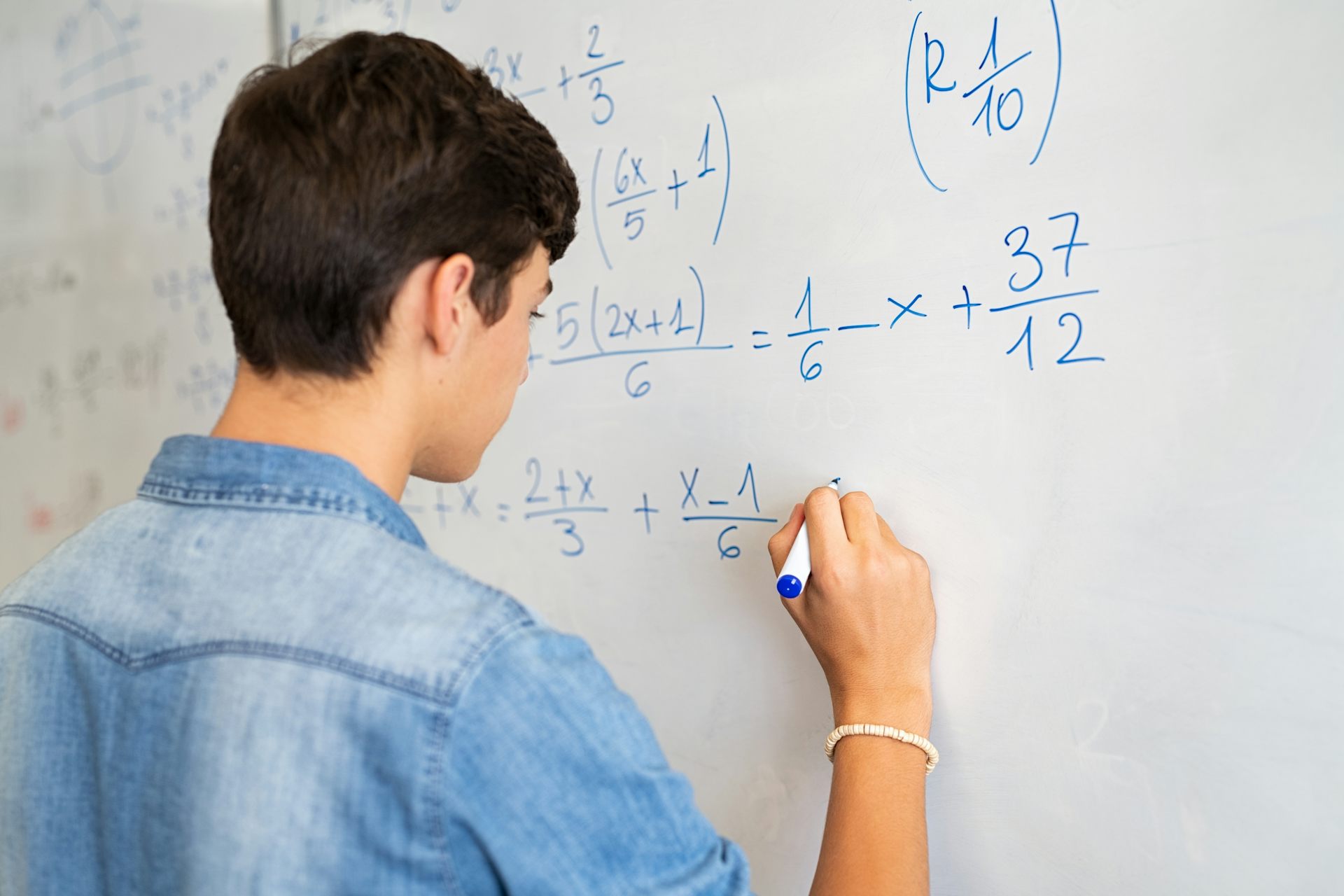 Un adolescent écrit des équations mathématiques au tableau