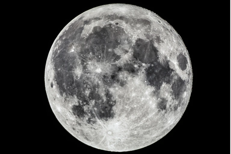 A black and white photograph of a full Moon shows craters, rays and basins.