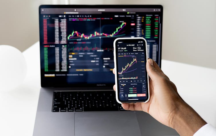 Laptop and mobile phone screens showing stock market prices
