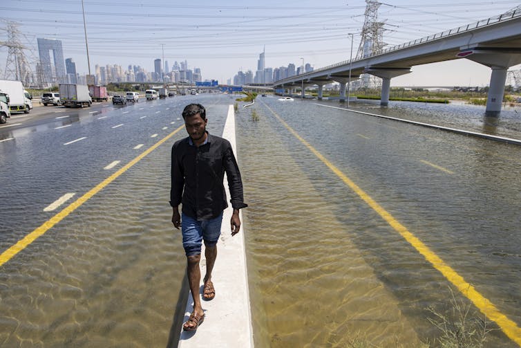 man walking along flooded highway