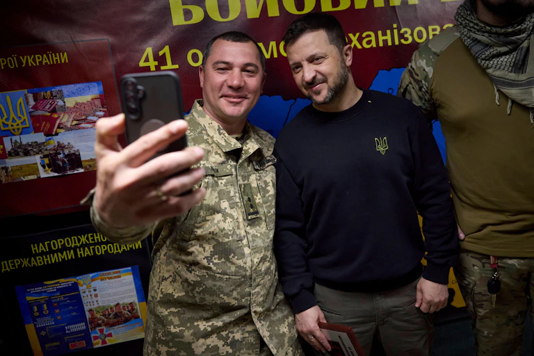 A Ukrainian soldier takes a selfie with VOlodymyr Zelensky, May 2024.