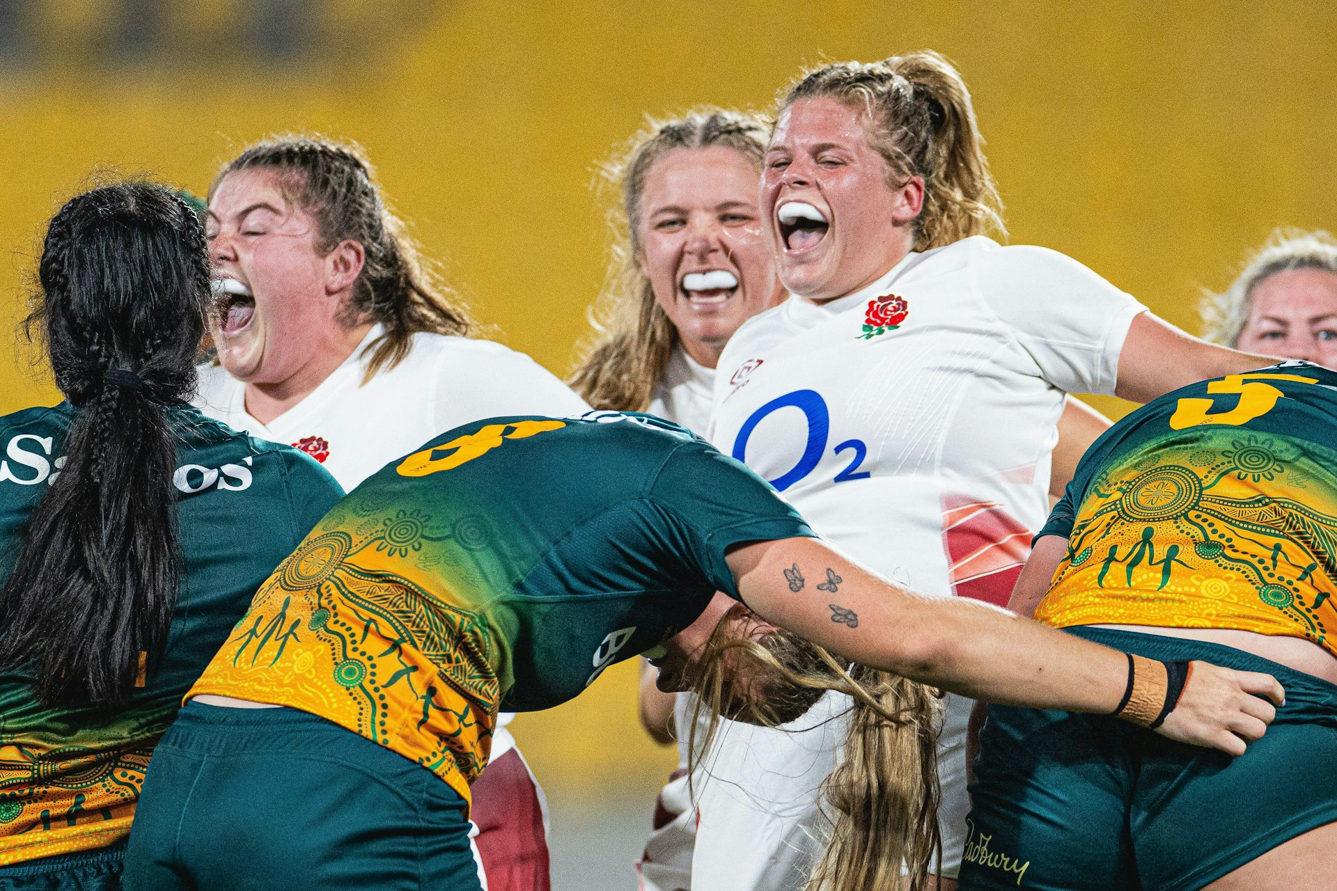 Three England rugby players in white shirts celebrate.